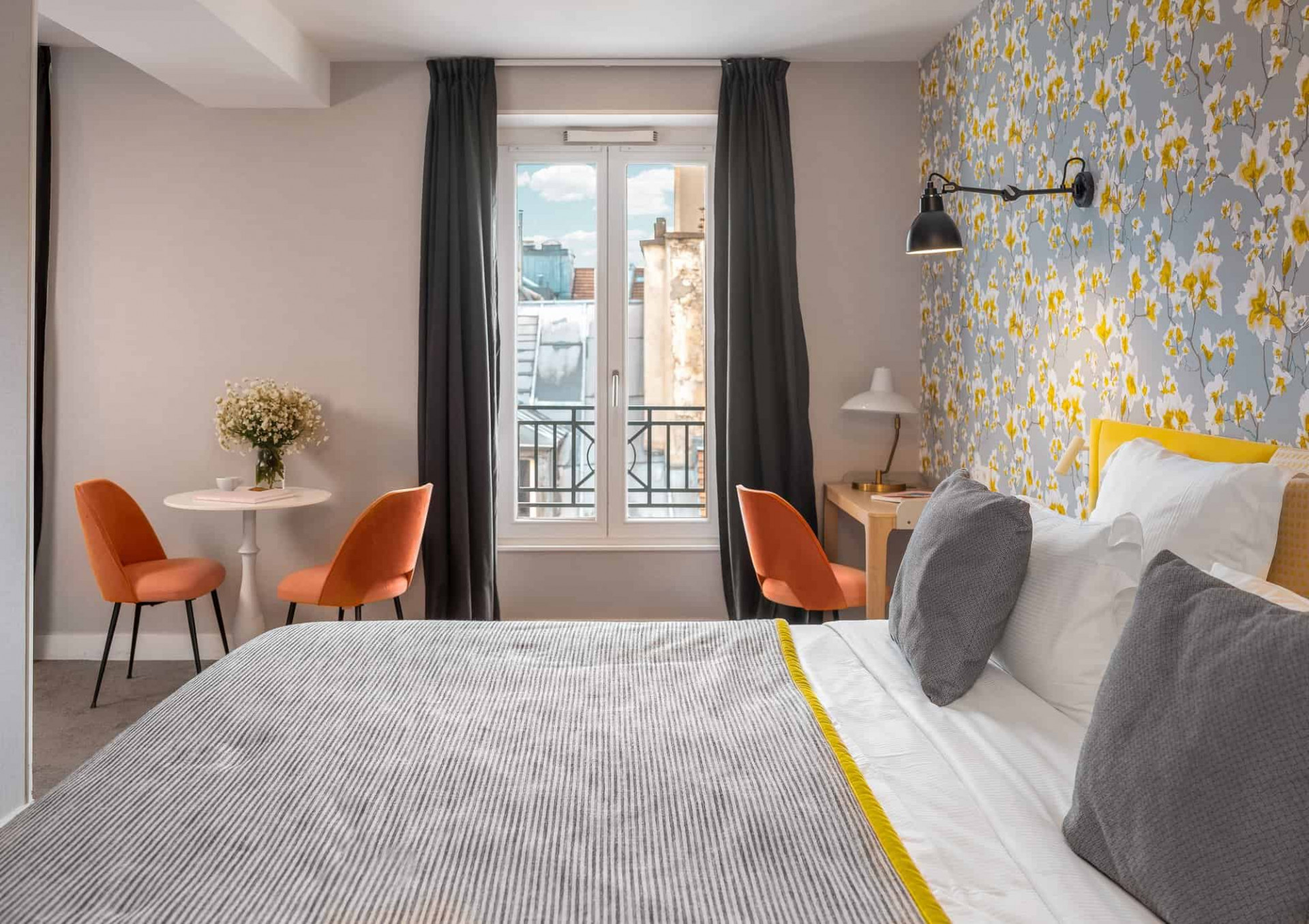 Room with flower wallpaper and a balcony with views of Paris at boutique hotel Le Mareuil. 